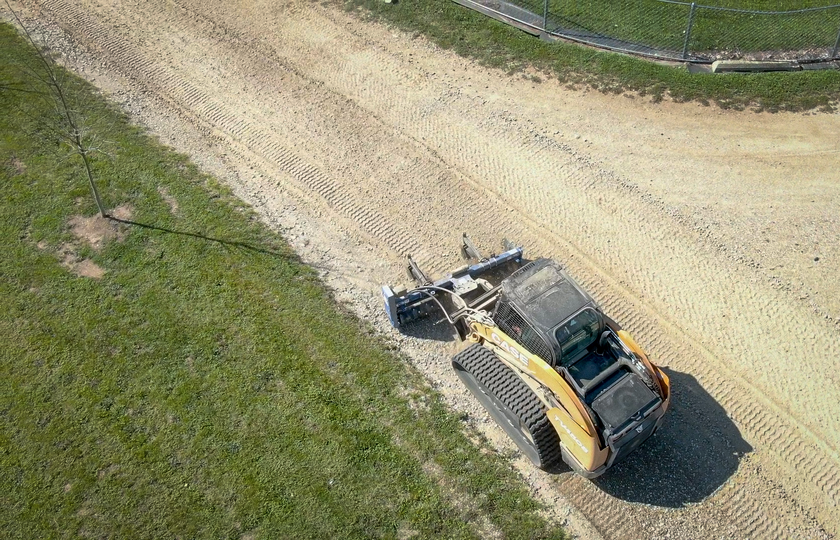 Aerial shot of case skid steer with a power rake working on a gravel driveway with windrows