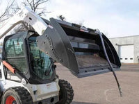 Thumbnail for A Bobcat skid steer, with its wide bucket lowered and a powerful hammer attachment at the ready, sits idle in a parking lot.