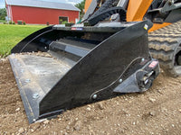 Thumbnail for A close-up of a skid steer bucket with a worn-out cutting edge, resting on a pile of dirt in front of a red barn.