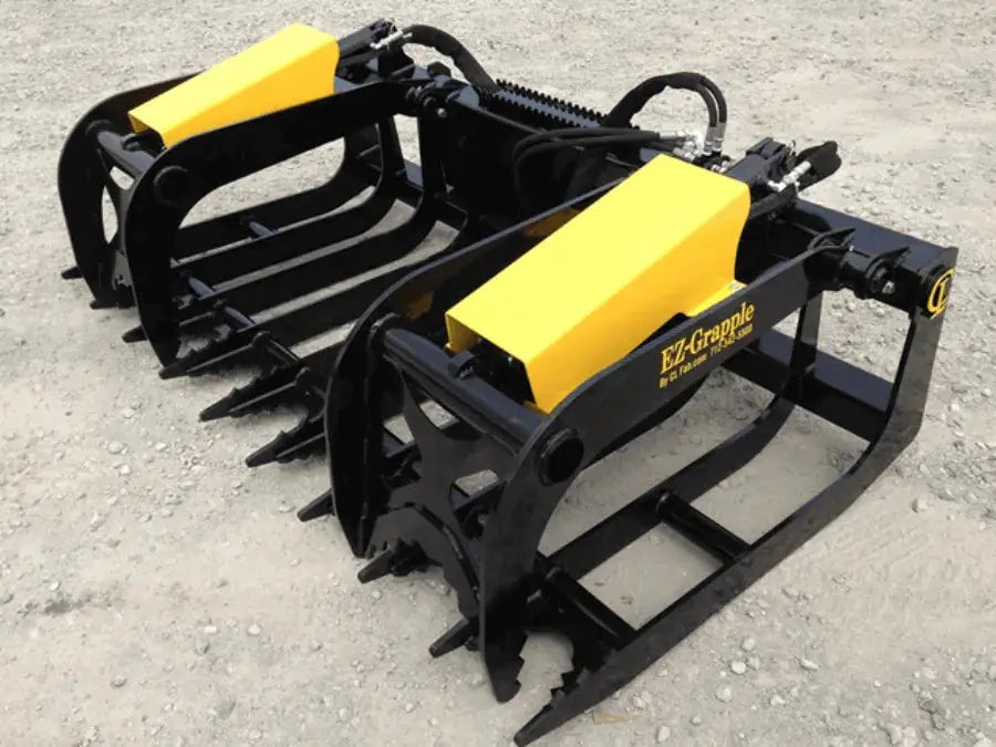 The image shows a pair of CL Fabrication grapple buckets sitting on a pile of dirt. The grapple buckets are black and yellow and have the words “EZ-Grapple” written on them in white letters.