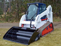 Thumbnail for A skid steer loader with a hydra bucket attachment, parked on a lush green field.