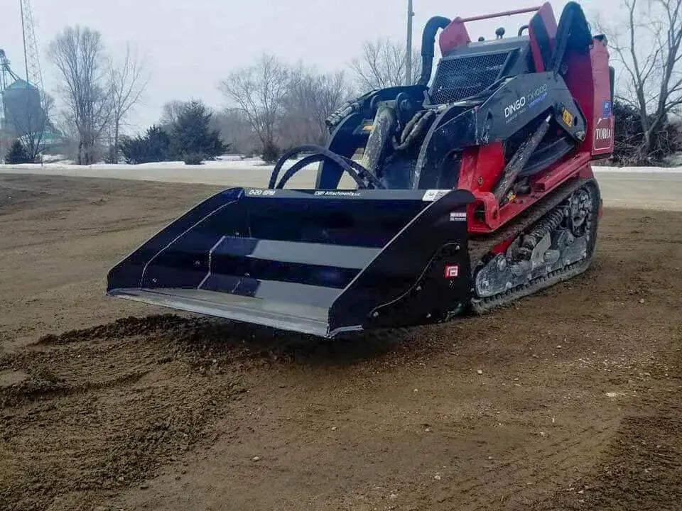 A Toro Dingo TCD skid steer loader with a mini hydra-bucket attachment sitting on a dirt field. 