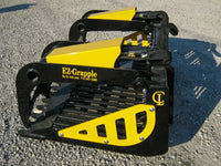 Thumbnail for A yellow and black EZ-Grapple bucket attachment sitting on a gravel road