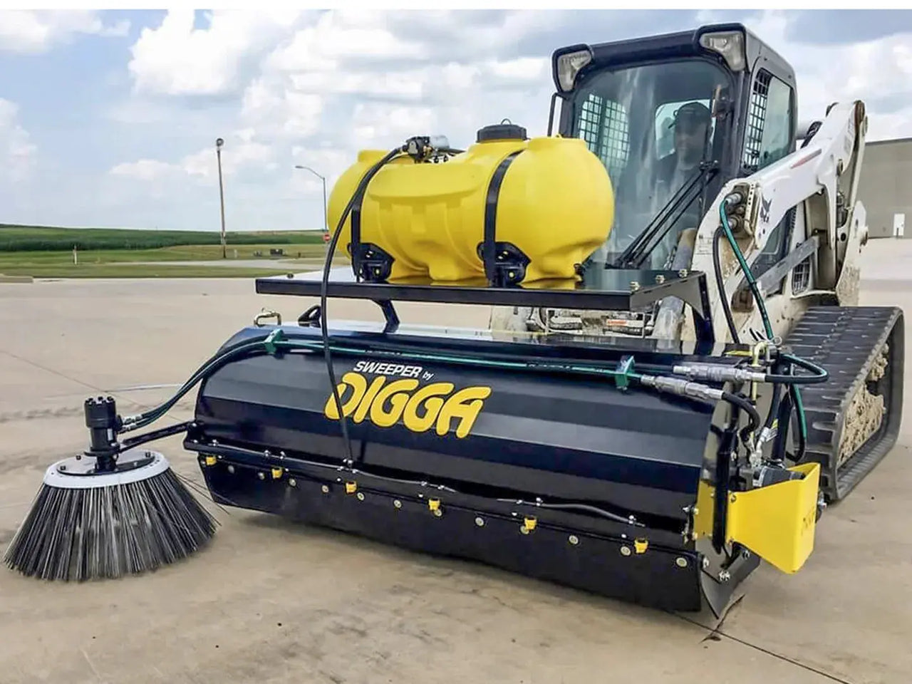 A Digga Sweeper Bucket Broom Attachment in action, sweeping up debris on a paved surface.